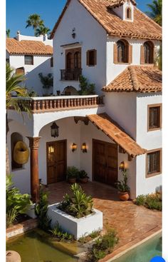 a large white house with brown roofing and palm trees in front of the house