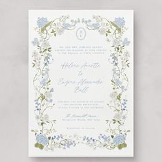 a wedding card with blue flowers and greenery on the front, in white paper