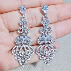 Elegance, sparkle and fluid motion define this exquisite pair of bridal earrings. All it takes is a simple glance at this unique design to see its extremely classy look that will add glamour and sophistication to any bridal gown or formal ensemble. Length: 2" (approx. 5cm); Width: 1" (approx. 2.3cm); Weight: 12g Choose between Rose Gold, Silver and Yellow Gold finishes. To make your choice select from the dropdown menu. Hypoallergenic - lead, nickel and cadmium free. Elegant Cubic Zirconia Bridal Earrings For Evening, Elegant Diamond White Crystal Bridal Earrings, Dazzling Crystal Bridal Earrings With Elegant Design, Elegant Crystal Bridal Earrings In Diamond White, Glamorous Sparkling Diamond Wedding Earrings, Glamorous Sparkling Diamond Earrings For Wedding, Glamorous Drop Diamond Earrings For Wedding, Glamorous Elegant Drop Diamond Earrings, Diamond White Elegant Bridal Earrings For Party