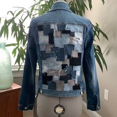 a blue jean jacket is on display in front of a potted plant and vase