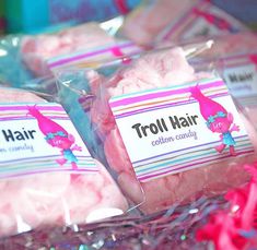 three bags of troll hair candy sitting on top of a pile of confetti