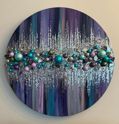 a circular painting with blue, purple and green ornaments hanging from it's sides