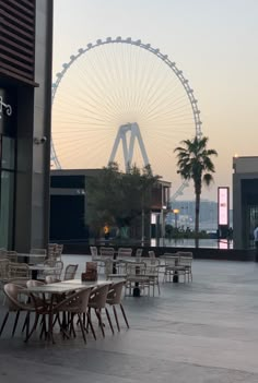 tables and chairs are lined up in front of a ferris wheel