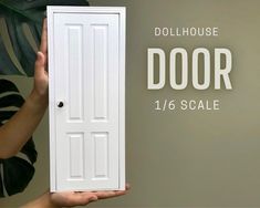 a person holding up a door with the words dollhouse door 1 / 6 scale