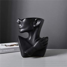 a black sculpture sitting on top of a white table next to a book and pen