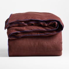 a brown blanket with blue piping is folded up on a white surface and it's edges are slightly down