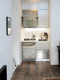 a kitchen with white cabinets and stainless steel appliances on the counter top, along with wood flooring