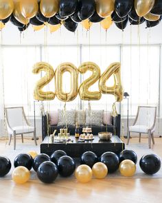 a room filled with balloons and black and gold decorations for a new year's eve party