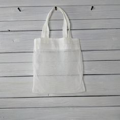 a white tote bag hanging on a wooden wall