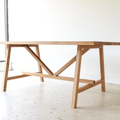 a wooden table sitting on top of a white floor next to a glass window in a room