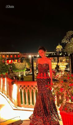 a woman in a red and black dress standing on a balcony