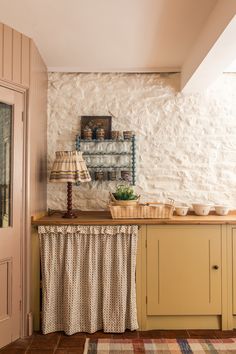 a kitchen with yellow cabinets and an old fashioned lamp on the side table in front of it