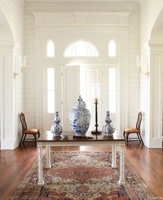 a table with two vases on top of it in front of a large doorway