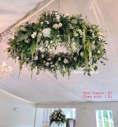 an overhead floral arrangement hanging from the ceiling in a marquee at a wedding