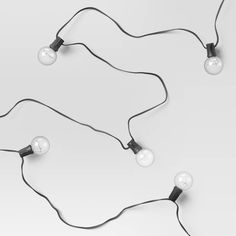 three lights that are connected to each other on a white surface with black wires and plugs