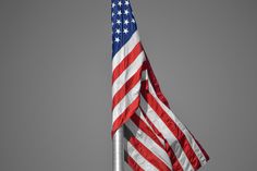 an american flag flying in the wind on a gray day with no clouds behind it