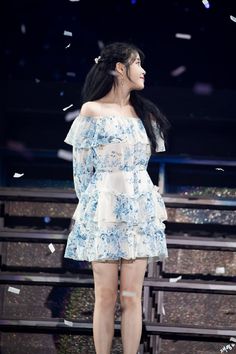 a woman standing on top of a stage wearing a blue and white frilly dress