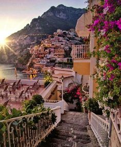 stairs lead down to the beach with flowers growing on them and mountains in the background