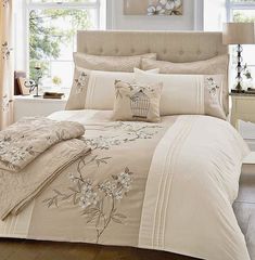 the comforter is made up with white flowers and birds in a cage on it