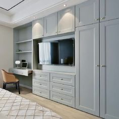 a bedroom with white cabinets and a television mounted on the wall, along with a bed