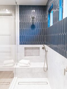 a bathroom with blue and white tile on the walls, shower head, and bathtub