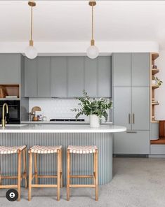 two stools sit in front of an island with marble countertops and gray cabinets