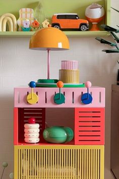 a toy kitchen with an orange lamp next to it and toys on the shelf behind it