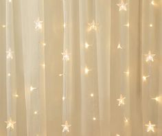 a curtain with white stars on it in front of a light filled wall and window