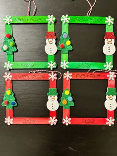 three frames with snowmen and christmas trees on them, hanging from twine strings