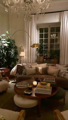 a living room filled with lots of furniture and a chandelier hanging from the ceiling