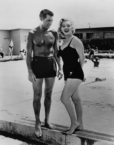 a man and woman standing on the edge of a swimming pool in swimsuits