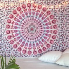 a large pink and white wall hanging over a bed in a bedroom next to a plant