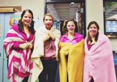 four women in pink and yellow robes are posing for a photo with one woman wrapped in a towel