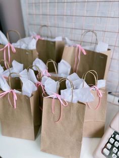 small brown paper bags with pink ribbon tied around them sitting on a table next to a calculator