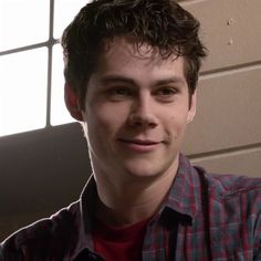 a close up of a person wearing a red and blue shirt with a brick wall in the background