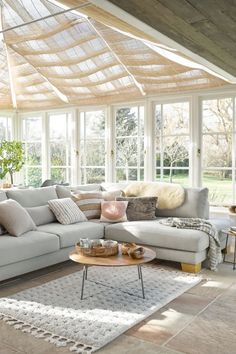 a living room filled with lots of furniture and large windows in the ceiling above it