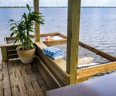 a wooden dock with two chairs and a potted plant on the deck next to it