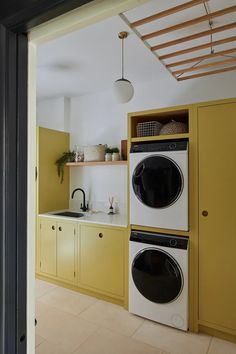 a kitchen with yellow cabinets and white appliances in it's center island, next to a washer and dryer