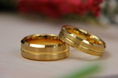 two gold wedding rings sitting next to each other