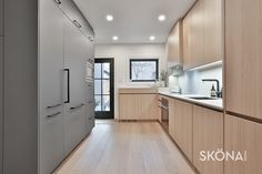 an empty kitchen with wooden floors and white walls, along with light wood cabinetry