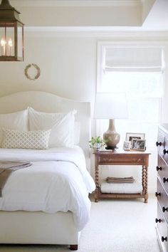 a bedroom with white linens and pillows on the bedspread next to a night stand