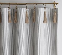 a curtain with tassels hanging from it's rod, in front of a white wall