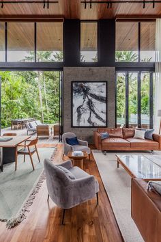 a living room filled with lots of furniture next to large windows and wooden flooring