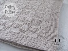 a crocheted blanket sitting on top of a white bed sheet with the words knitting pattern written across it