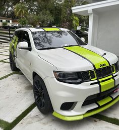 a white jeep with neon yellow stripes parked in front of a house on the street