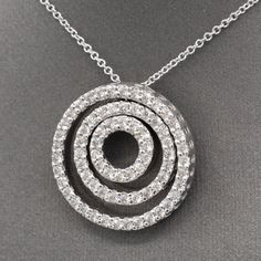 This necklace brings all the sparkle and bling! Three concentric circles are attached at the top (the middle circle floats) to form a dynamic and powerful piece. The circles are encrusted with natural earth-mined diamonds measuring 1.5mm each, for a total approximate carat weight of 72 stones equaling 1.08cttw. The diamonds are fully cut round brilliant, H/I color and SI2 average clarity. There are no eye visible inclusions and the stones are bright white and sparkly! The pendant measures just o Spiral Cubic Zirconia Jewelry For Anniversary, Fine Jewelry With Spiral Brilliant Cut, Cubic Zirconia Jewelry With Halo Design And Circle Shape, Halo Designed Circle Cubic Zirconia Jewelry, Spiral White Gold Jewelry With Brilliant Cut, White Gold Spiral Jewelry With Brilliant Cut, White Gold Jewelry With Brilliant Cut In Spiral Shape, Fine Jewelry With Spiral Shape And Diamond Accents, Fine Jewelry With Diamond Accents In Spiral Shape