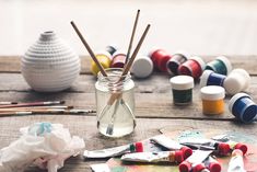 an assortment of crafting supplies including paint, brushes and spoons on a table