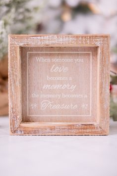 a wooden frame with a quote on it sitting next to some christmas trees and other decorations