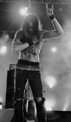 a shirtless man standing on top of a stage with his hands in the air