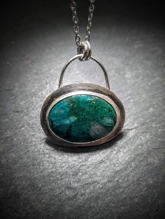 "Beautiful piece of gem silica chryscolla mounted in a handforged silver bezel.  Pendant measures 1.6\"(42.4mm) by 1.4\"(37.6mm) and weighs 0.4 oz. Pendant ships with a 20\"silver chain with lobster clasp and a gift box." Green Sterling Silver Charm Necklace With Round Pendant, Silver Chrysocolla Necklace With Large Stone, Green Soldered Round Pendant Jewelry, Silver Oval Apatite Jewelry, Silver Cabochon Gemstone Pendant, Silver Jade Cabochon Necklace, Silver Chrysocolla Cabochon Jewelry, Silver Glass Cabochon Necklace, Gem Silica